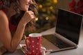 Closeup on woman having christmas cookies and usign laptop Royalty Free Stock Photo