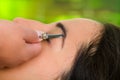 Closeup woman headshot profile,lying with eyes closed and hand holding tweezer pulling eyebrow