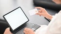 Closeup woman is holding a credit card while using a computer tablet. Royalty Free Stock Photo