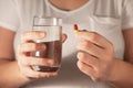 Closeup of a woman holding a medicine pill and a glass of water Royalty Free Stock Photo