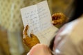 Closeup of a woman holding a piece of paper in her henna-tattooed hands,with a text written in Hindi