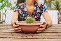 Closeup of a woman holding a pot of cactus in the terrace