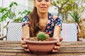 Closeup of a woman holding a pot of cactus in the terrace