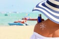 Closeup woman holding the sunblock bottle cream in hand, with sunblock lotion cream applied to her back and draw is the sun, at Royalty Free Stock Photo