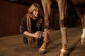 Closeup woman horse owner putting bandage on animal leg to prevent injury