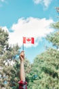Closeup of woman human hand arm waving Canadian flag against blue sky. Proud citizen man celebrating national Canada Day on 1st of Royalty Free Stock Photo