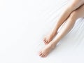 Closeup woman legs on white bed with over light form window, beauty and skin care concept, selective focus