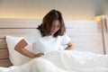 Closeup Woman lying on Bed looking sick in the Bed room. Beautiful young asian woman lying on bed and holding hands on her stomach Royalty Free Stock Photo