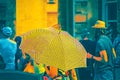 Closeup of woman mostly hidden by bright black and white umbrella walks through crowded street with tourists and performer-singer