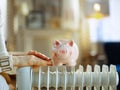 Closeup on woman near radiator with piggy bank warming hands Royalty Free Stock Photo