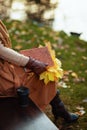 Closeup on woman with notebook, yellow leaves and cup of coffee