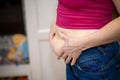 Closeup of woman pinching belly fat.