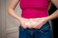 Closeup of woman pinching belly fat.