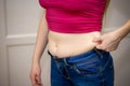 Closeup of woman pinching belly fat.