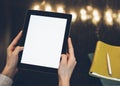 Closeup of a woman pointing finger to an blank display of the tablet with a blue color in a homelike atmosphere on warm bokeh back