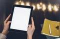 Closeup of a woman pointing finger to an blank display of the tablet with a blue color in a homelike atmosphere on warm bokeh back