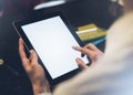 Closeup of a woman pointing finger to an blank display of the tablet with a blue color in a homelike atmosphere on warm bokeh back