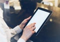 Closeup of a woman pointing finger to an blank display of the tablet with a blue color in a homelike atmosphere on warm bokeh back