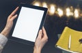 Closeup of a woman pointing finger to an blank display of the tablet with a blue color in a homelike atmosphere on warm bokeh back