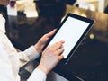 Closeup of a woman pointing finger to an blank display of the tablet with a blue color in a homelike atmosphere on warm bokeh back