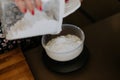 Closeup of a woman pouring the flour in the bowl on the weighing machine