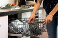 closeup of a woman putting plastic containers in a dishwasher, in a kitchen