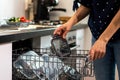 closeup of a woman putting plastic containers in a dishwasher, in a kitchen