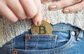 Closeup of a woman putting a single bitcoin in her jeans pocket