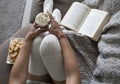 Closeup of woman reading book at home on couch with hot chocolatemilk and cookies Royalty Free Stock Photo