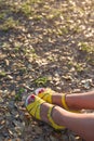 Closeup of woman`s feet in bright yellow sandals on the ground. Sunny summer day outdoors. woman walking in the park Royalty Free Stock Photo