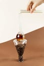 Closeup of woman`s hand holding test tube with oat milk pouring it into flask with coffee on conical glassware