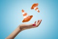 Closeup of woman`s hand levitating two orange safety cones on light blue background.