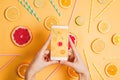 Closeup of woman`s hand with a smartphone making picture of various citrus fruits flatlay arrangement.
