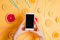 Closeup of woman`s hand with a smartphone making picture of various citrus fruits flatlay arrangement.