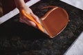 Closeup of woman`s hand tempering melted chocolate on a marble surface Royalty Free Stock Photo