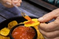 Closeup of woman`s hands while eating plantain chips served with Colombian traditional hogao Royalty Free Stock Photo