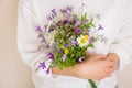 Closeup of woman`s hands holding beautiful bunch of wild flowers. Girl with summer bouquet at white wall Royalty Free Stock Photo