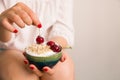 Closeup of woman`s hands holding bowl with organic homemade yogurt topped with oats and cherries. Royalty Free Stock Photo