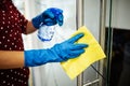 Closeup of woman`s hands wearing blue rubber protective gloves spraying with sanitizer and cleaning door handle at the office Royalty Free Stock Photo