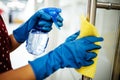 Closeup of woman`s hands wearing blue rubber protective gloves spraying with sanitizer and cleaning door handle at the office Royalty Free Stock Photo