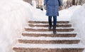 Closeup woman`s legs goes down on a snowy ladder, staircase. Winter park in the city during the day in snowy weather Royalty Free Stock Photo