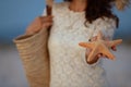 Closeup on woman on seashore at sunset showing starfish