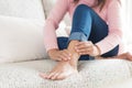 Closeup woman sitting on sofa holds her ankle injury