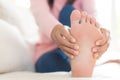 Closeup woman sitting on sofa holds her foot injury