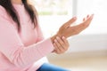 Closeup woman sitting on sofa holds her wrist hand injury, feeling pain. Health care and medical concept Royalty Free Stock Photo