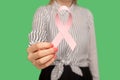 Closeup of woman in striped blouse holding pink ribbon, symbol of breast cancer awareness