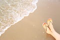 Closeup of woman with stylish flip  on sand near sea, space for text. Beach accessories Royalty Free Stock Photo