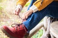 Closeup of woman tying boot shoe laces. Female enjoying hiking getting ready for outdoors excursion. Red boot and yellow jacket Royalty Free Stock Photo