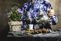 Closeup woman wearing beautiful blue dress pouring Arabic tea,  french dessert eclairs with custard and chocolate icing Royalty Free Stock Photo