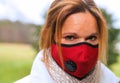 A closeup of a woman wearing a red antivwoman wearing virus protection mask